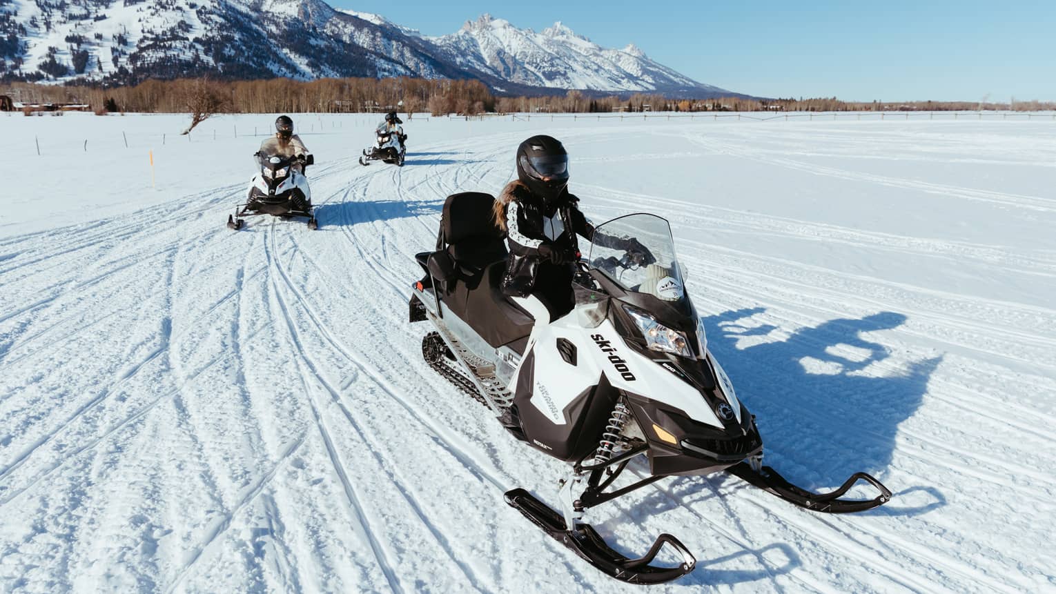 Three people on snowbmobiles.