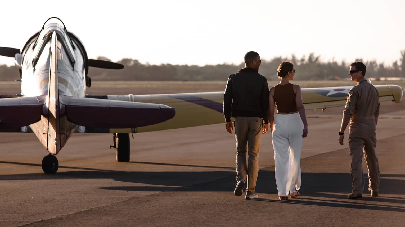 A group of people walking towards an old plane.