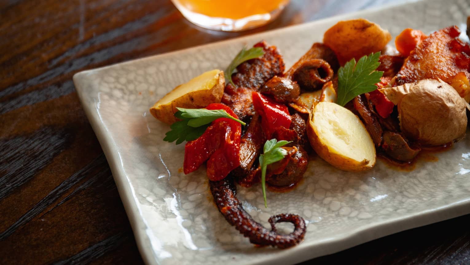 Octopus, potatoes, artichokes, and peppers grilled on a plate.