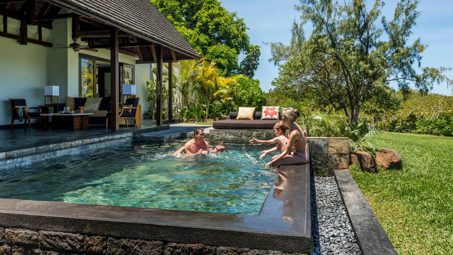 Couple, two children laugh, splash in sunny Garden Villa plunge swimming pool