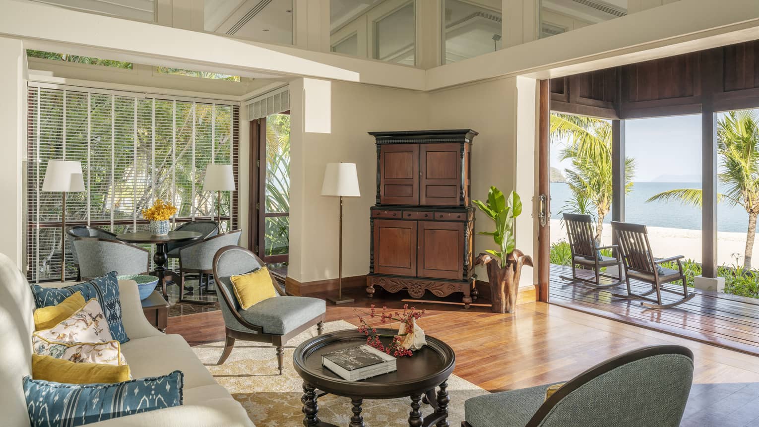 Living room with teak floors and opening to covered terrace looking out to beach
