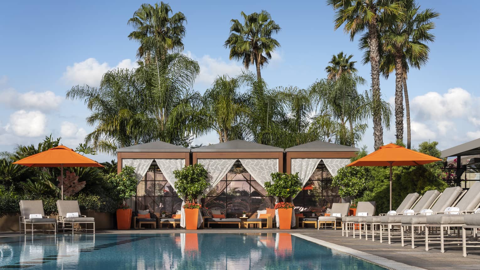 Outdoor pool with lounge chairs, umbrellas and cabanas.