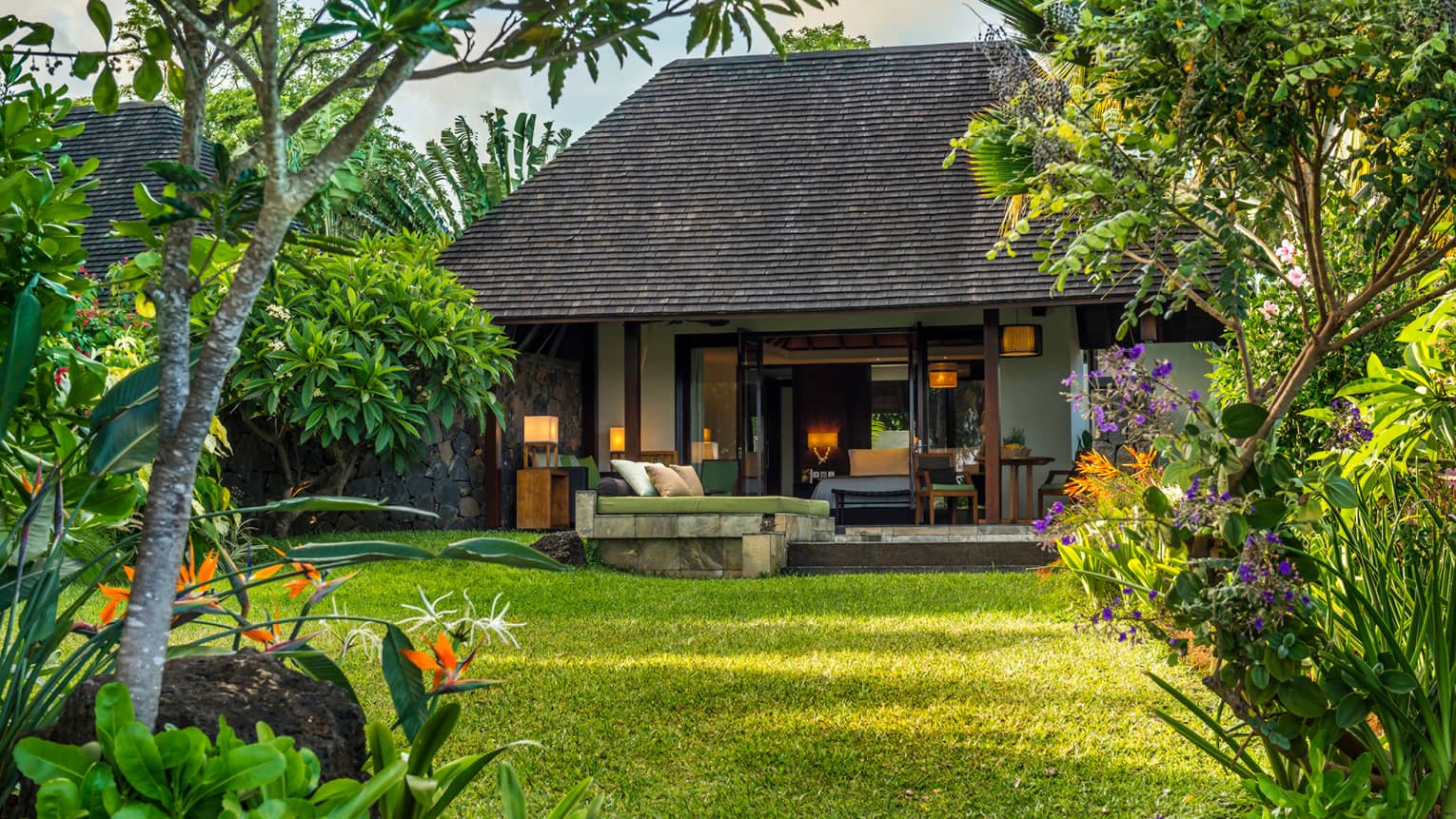 Garden Pool Villa view from across lawn to patio, lounge chairs, open bedroom door