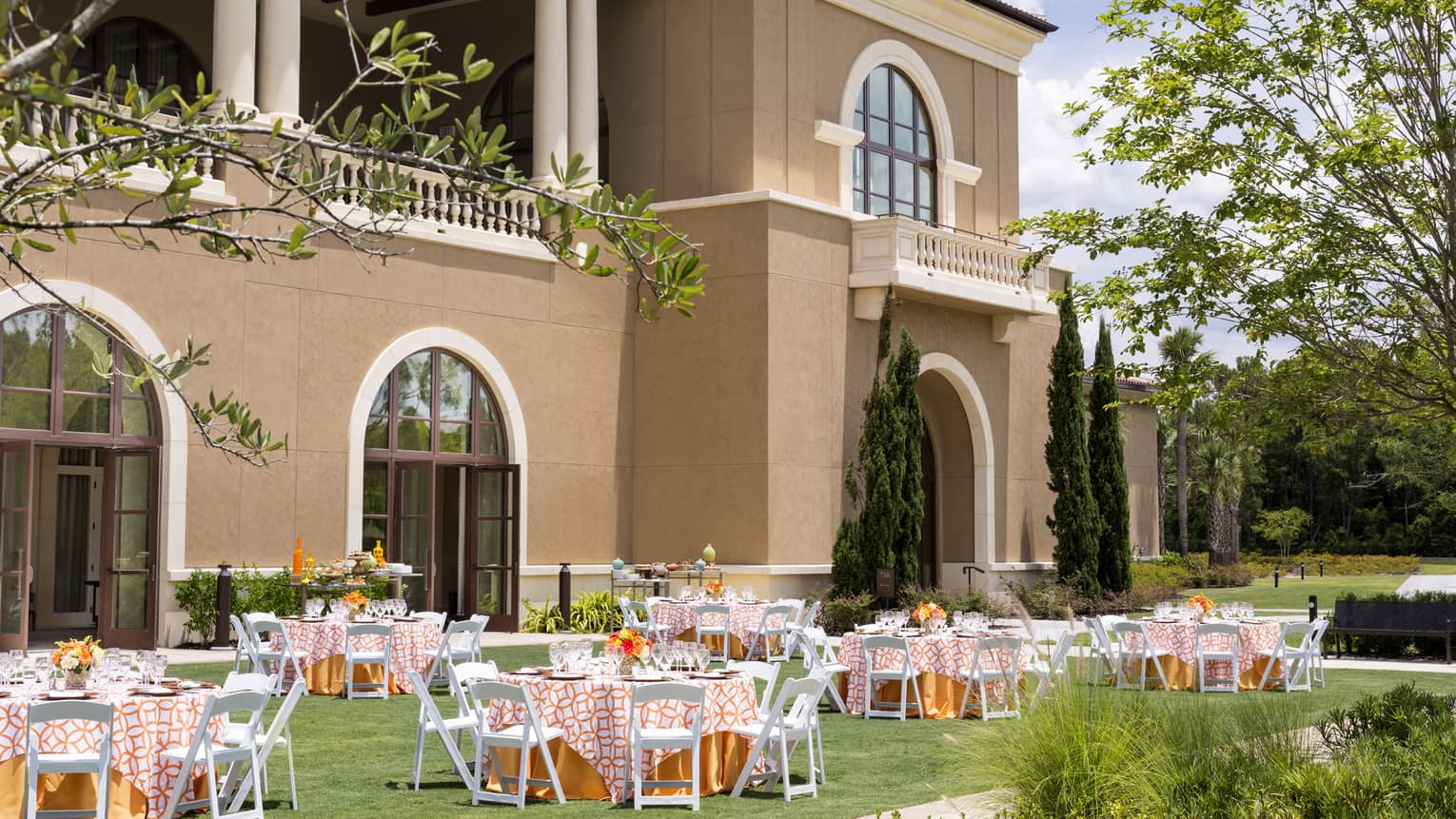 Garden wedding set up, round tables with orange linens, white chairs