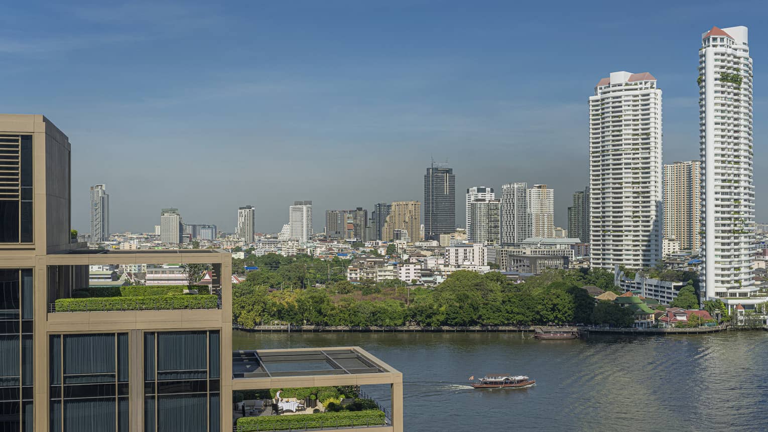 Hotel suites' outdoor patios, terraced on building, overlooking the Chao Phraya River and city