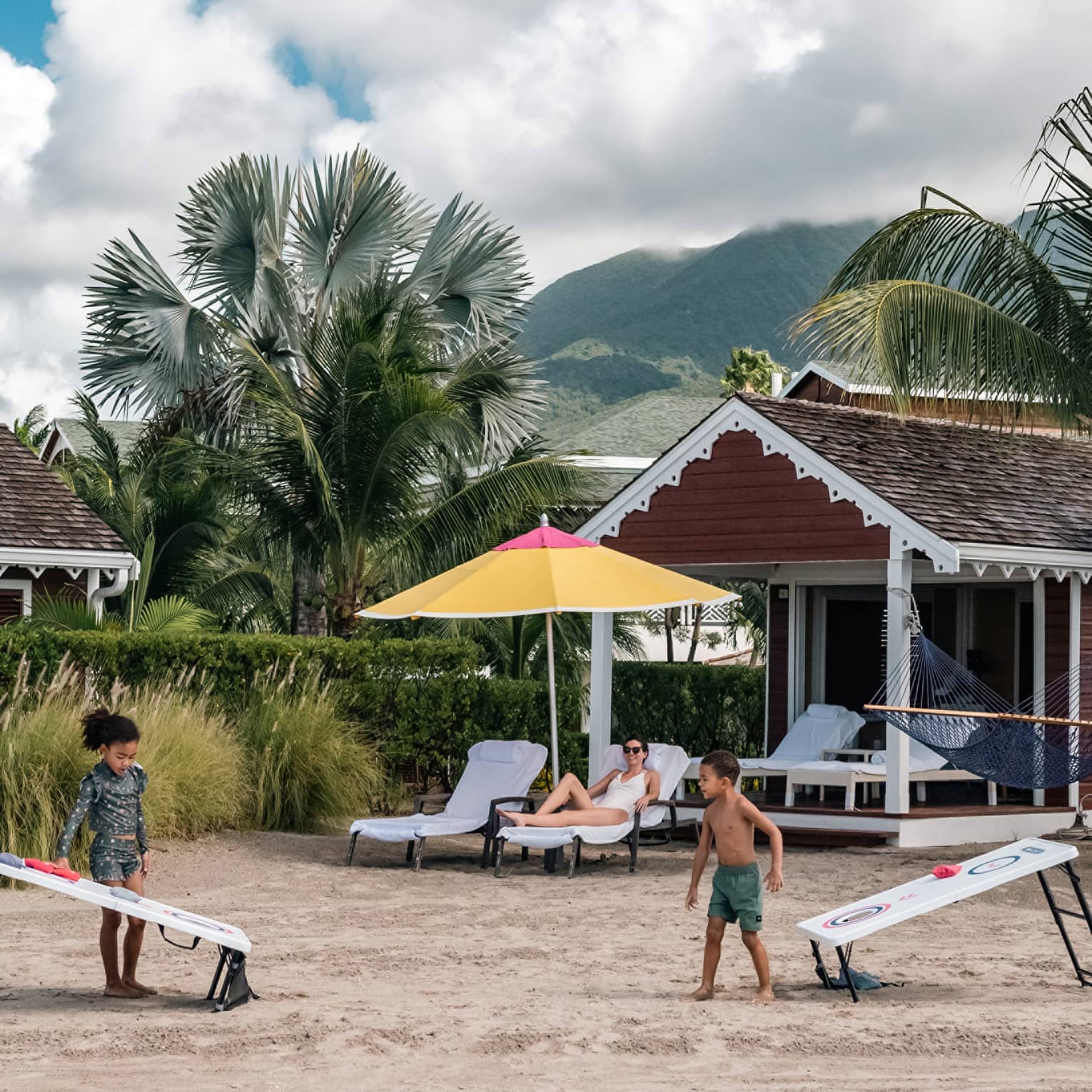 Beach cabana and kids playing corn hole on the beach