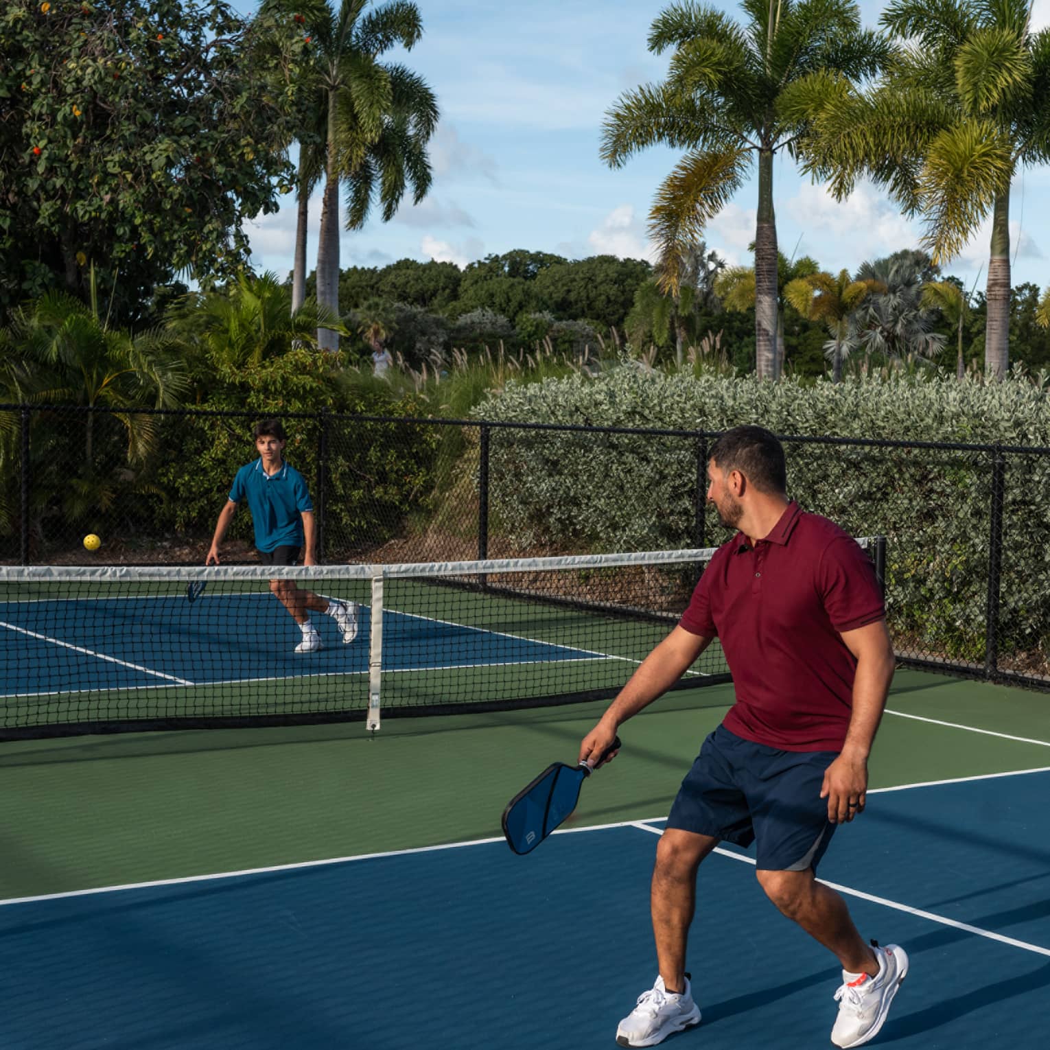 Guests playing pickleball on a pickleball court surrounded by palm trees