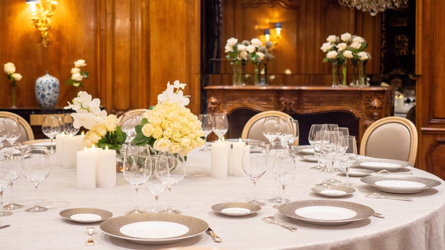 A dining table set with plates, wine glasses and floral arrangements in a private dining room