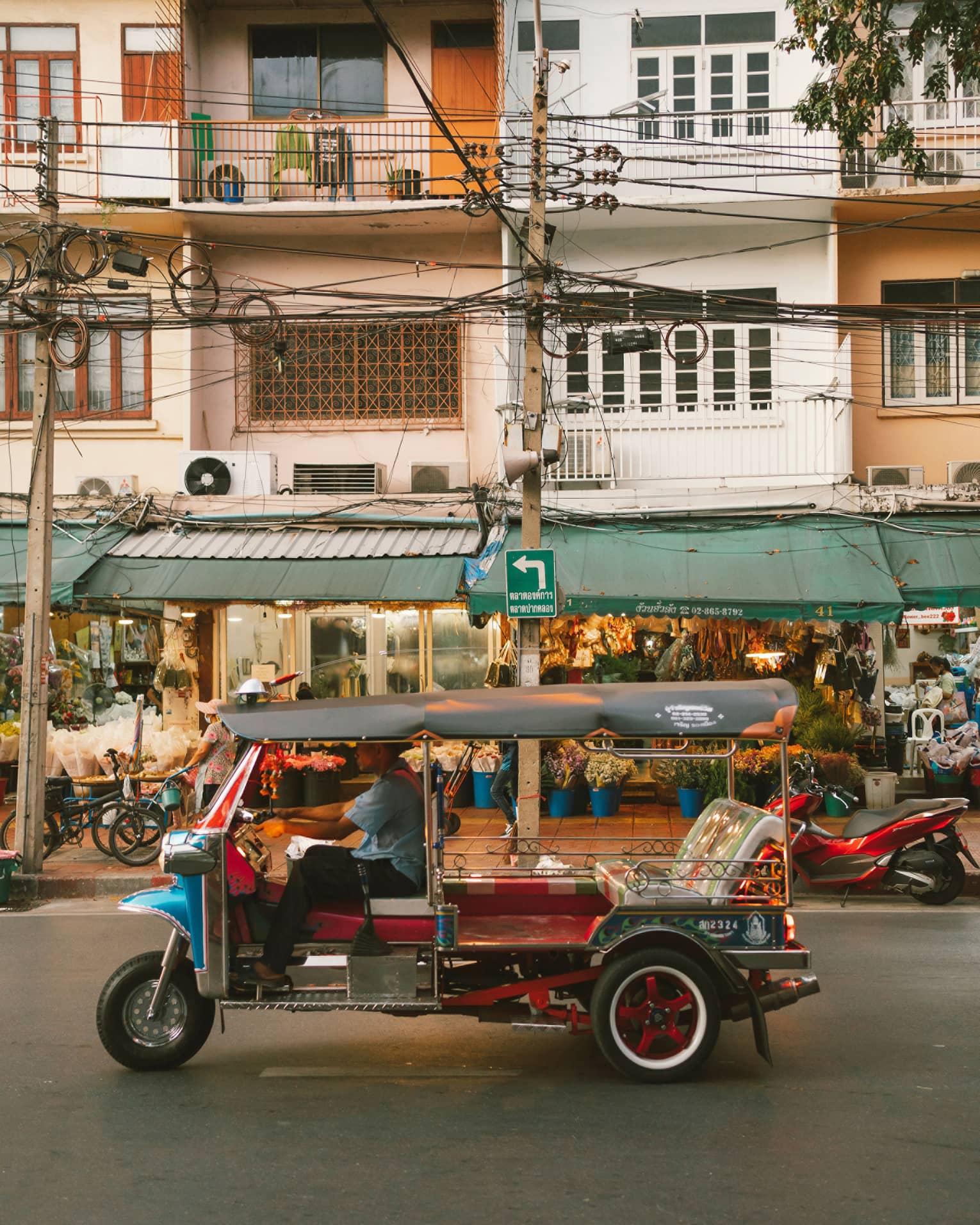 Colourful auto rickshaw parked in front of three-storey building with green awning