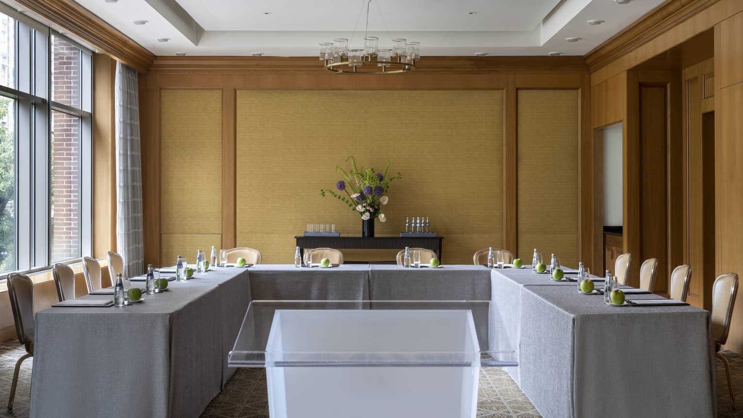 A U-shaped table with grey cloth and a clear podium in the middle.