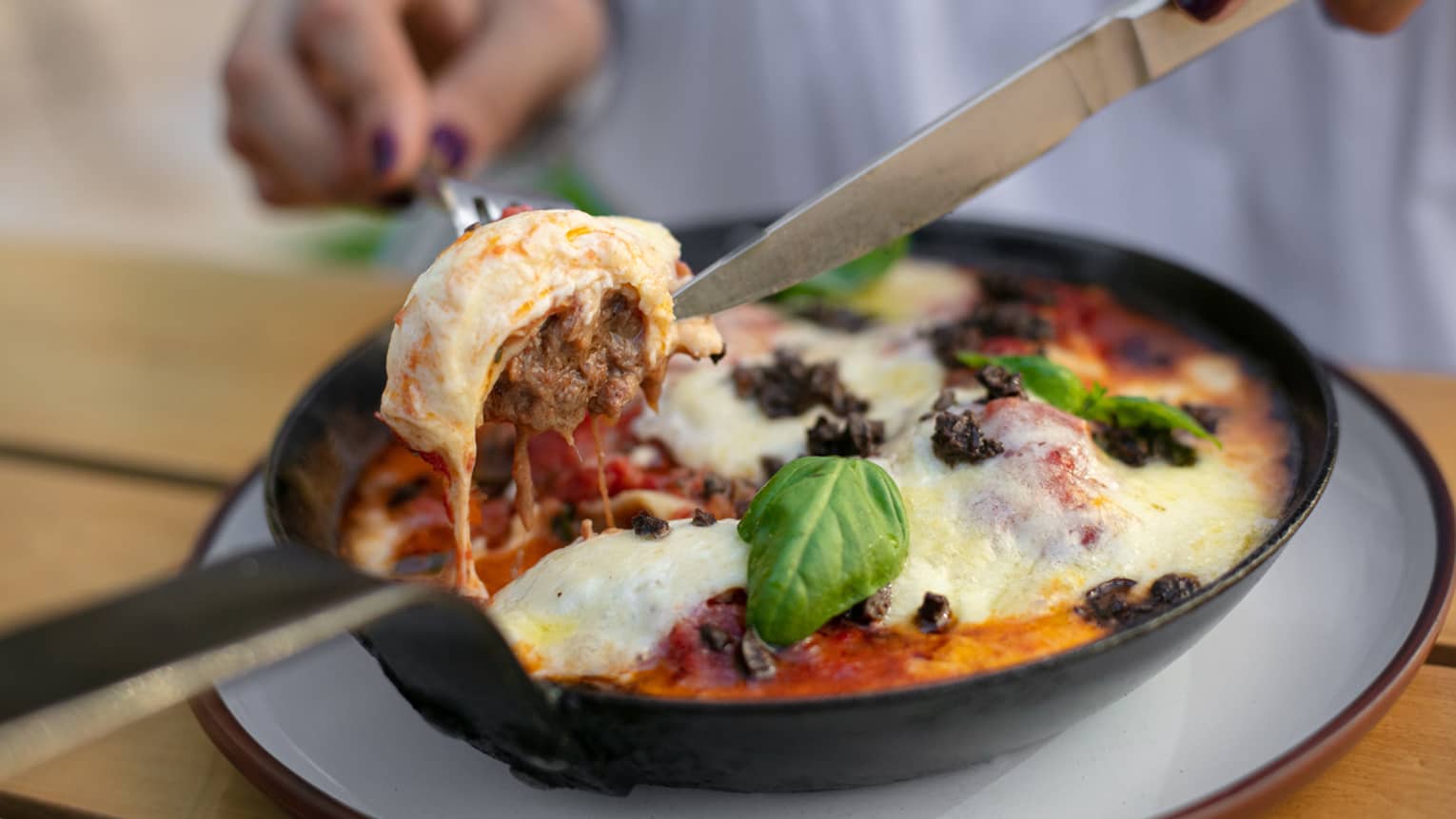 A braised short rib ravioli being cut into by a chef. 