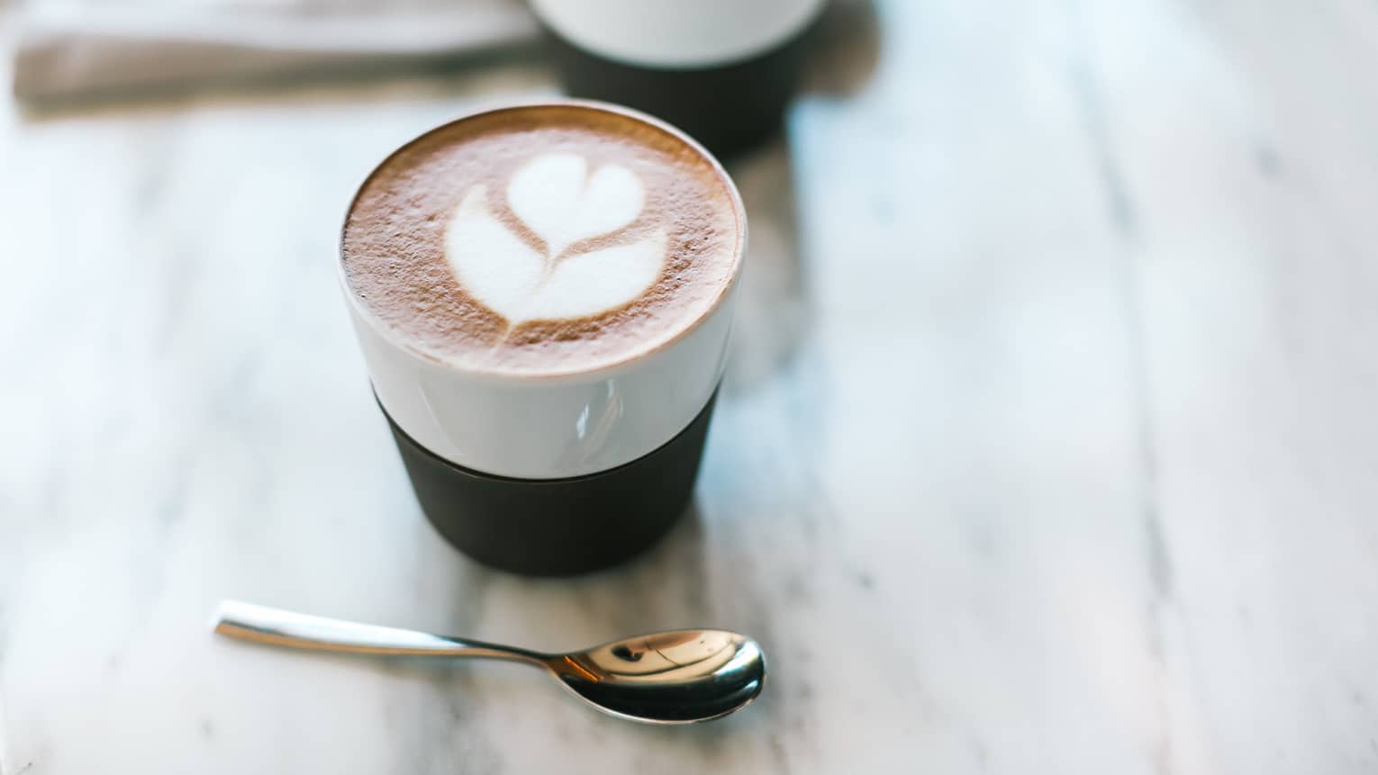 Seasons Barista Bar cappuccino with tulip drawn in foam, small silver spoon
