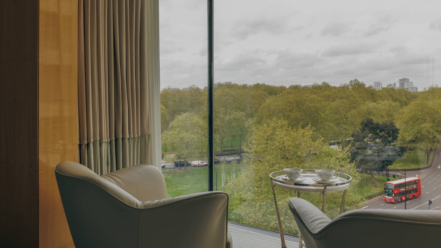 Two chairs face a wall of windows looking out to green space
