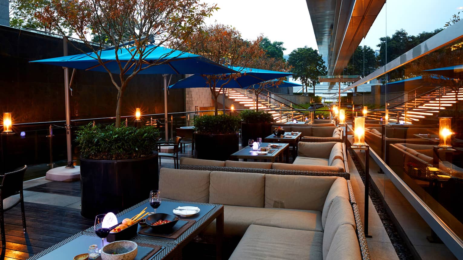 Foo rooftop patio lounge banquettes, potted trees, blue umbrellas