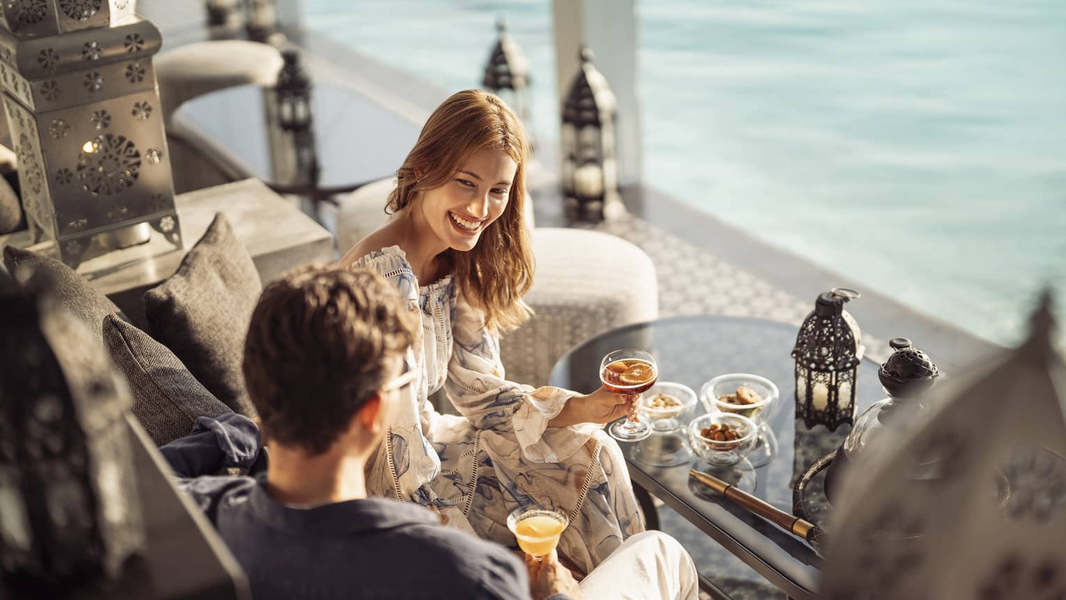 Smiling couple enjoys cocktails on the outdoor terrace of Al Barakat