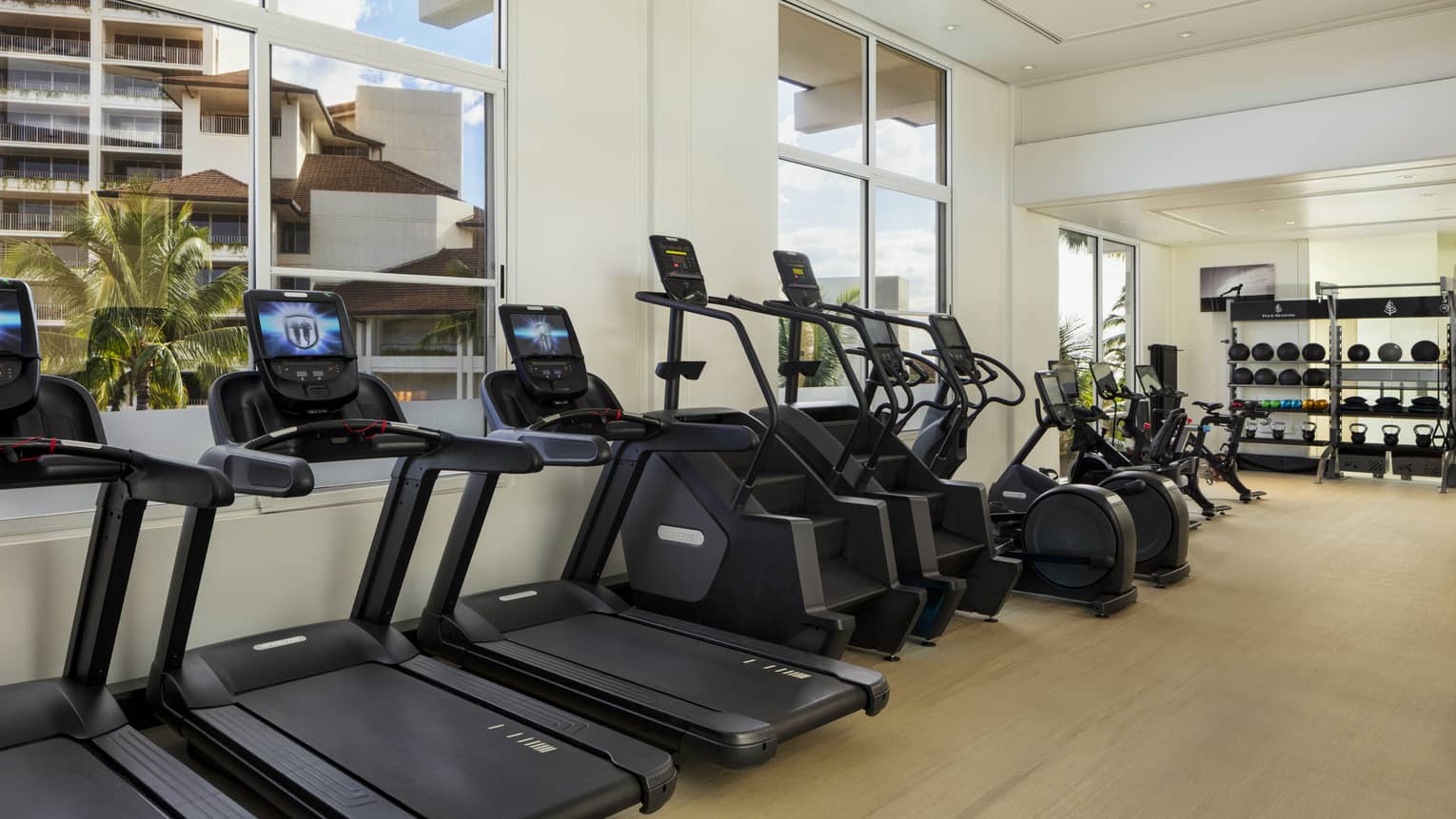 Three treadmills, two stair masters and four bikes stationed against a wall of windows at Four Seasons Resort Oahu fitness centre
