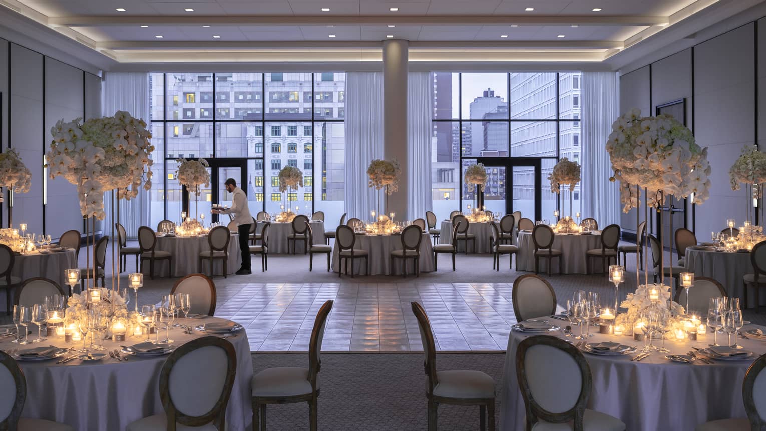 Four Seasons staff sets round table with candles in Palais des Possibles Ballroom