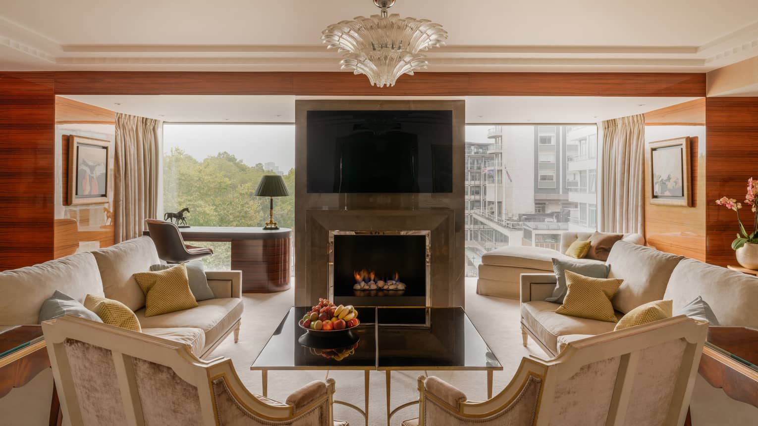 Elegant living room of Presidential Suite, with two sofas and two arm chairs, fireplace, TV and chandelier at Four Seasons Hotel London