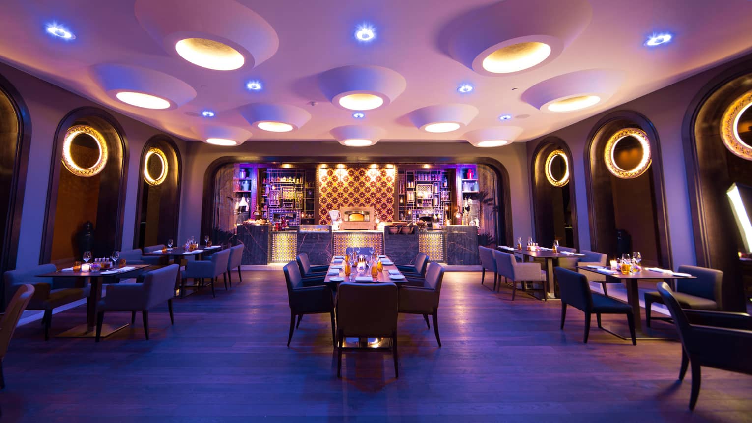 Candle-lit tables, chairs in Quattro dining room with large modern pot lights in white ceiling