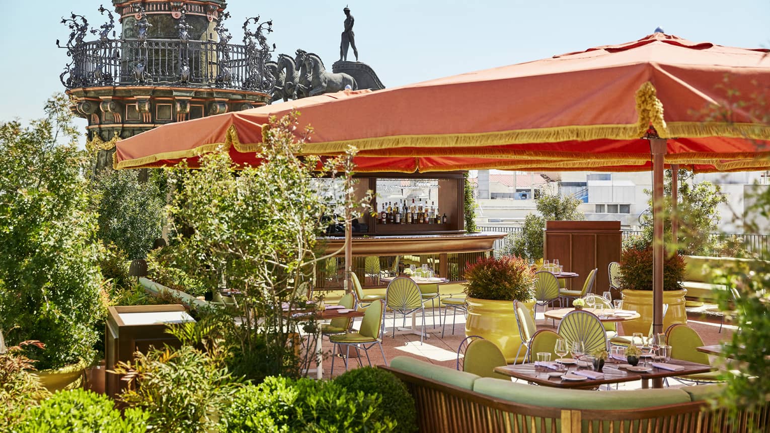 Brightly coloured Dani restaurant terrace with green decor and orange umbrellas over tables