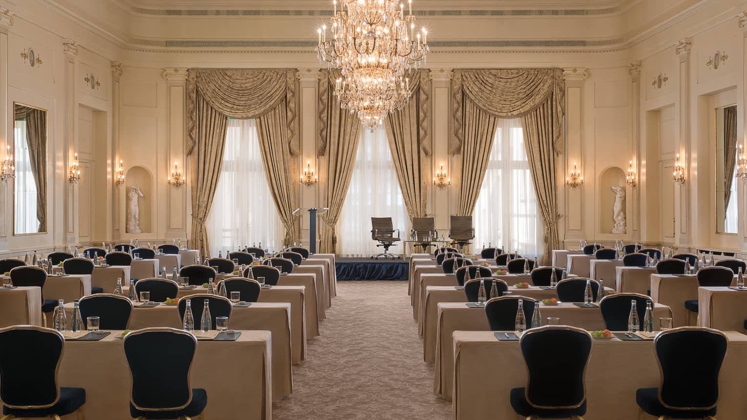 Salon des Nations rows of meeting tables, chairs facing conference stage and large crystal chandelier 