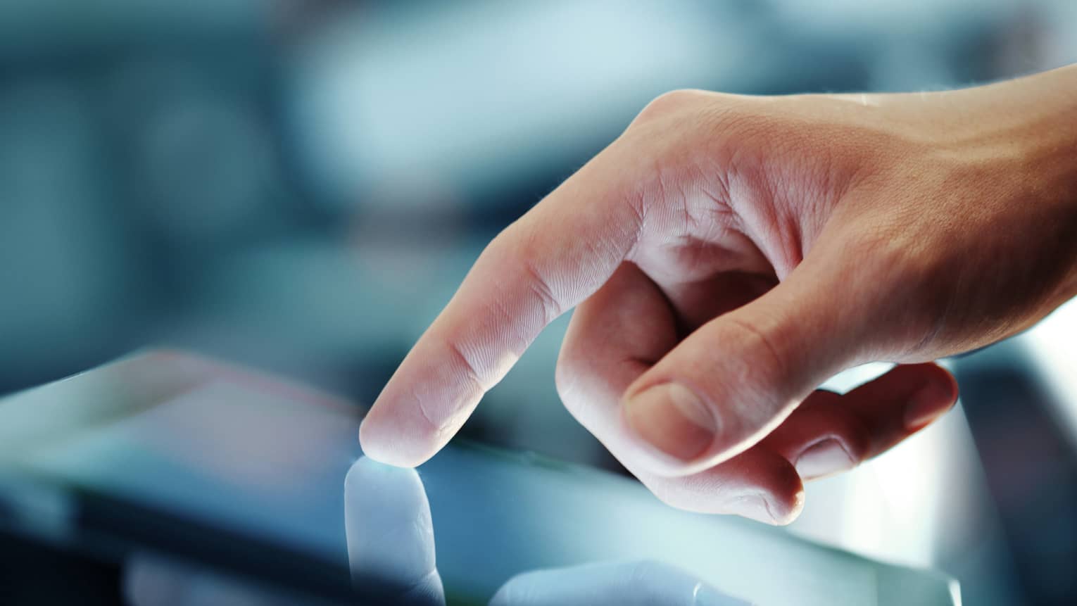 A hand with index finger extended touches the screen of a tablet