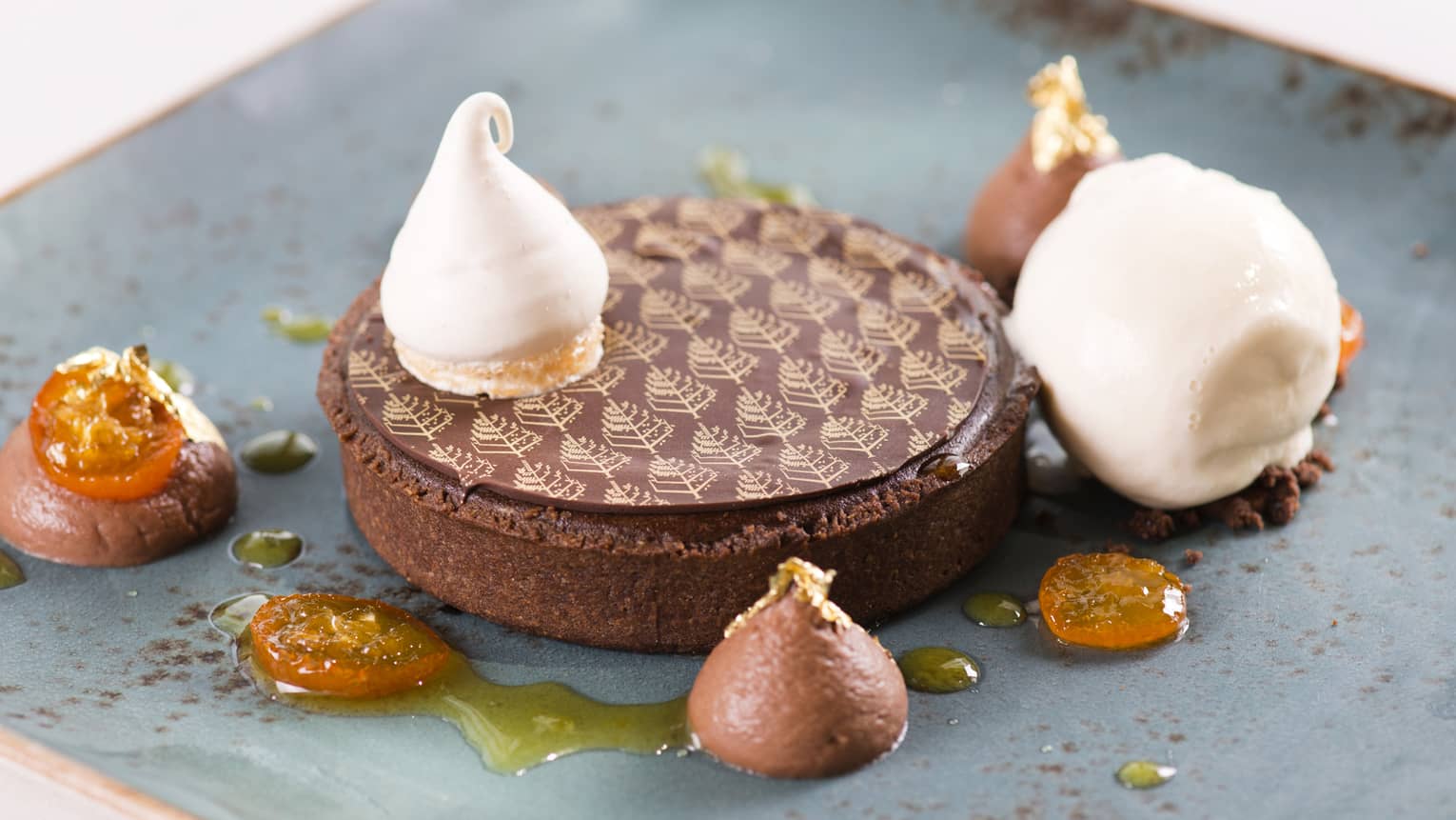 Tart covered by chocolate disc with Four Seasons logo print, small scoops of cream