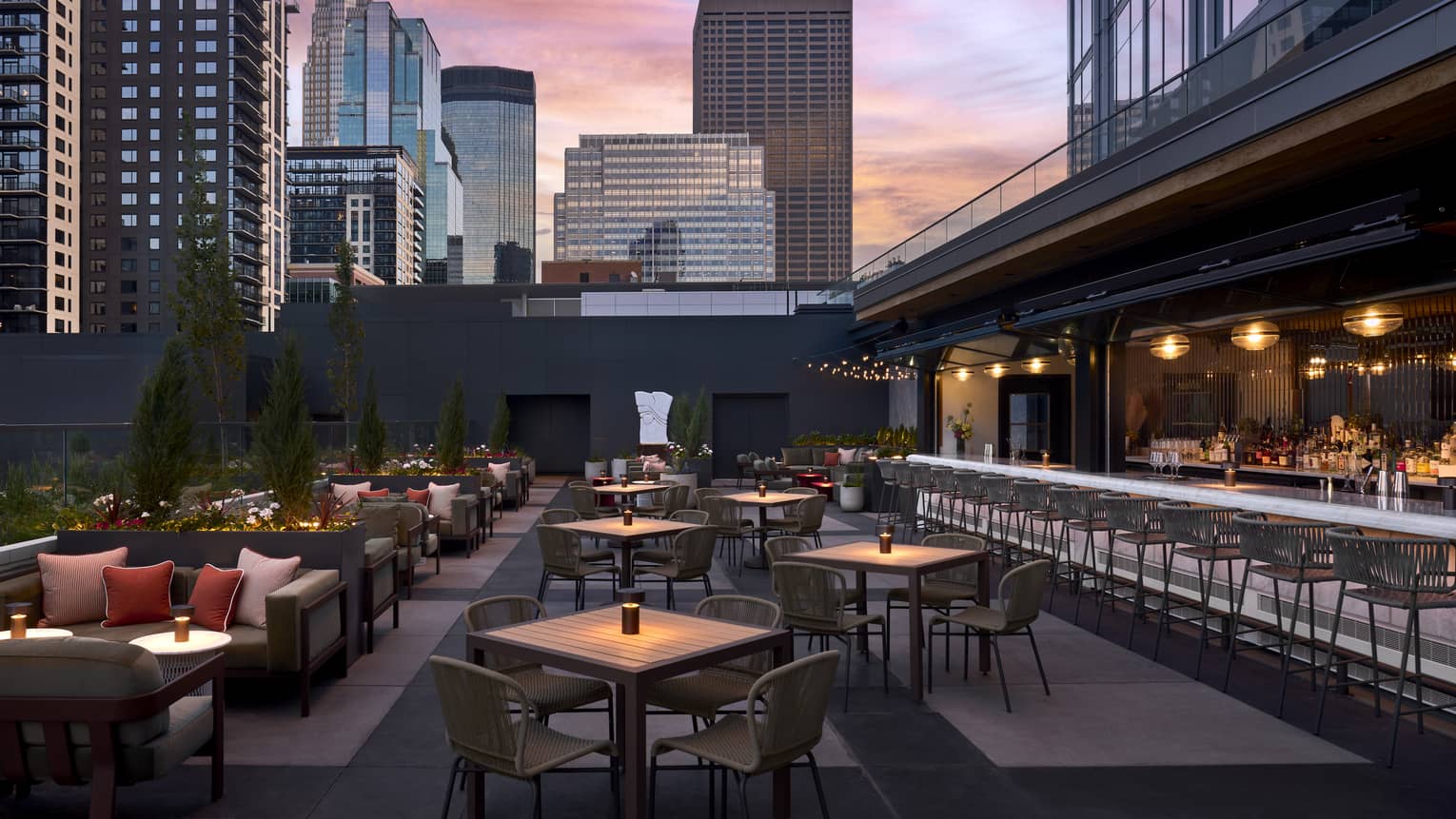 An outdoor plaza with sofas, tables, chairs and patio with a city in the background.