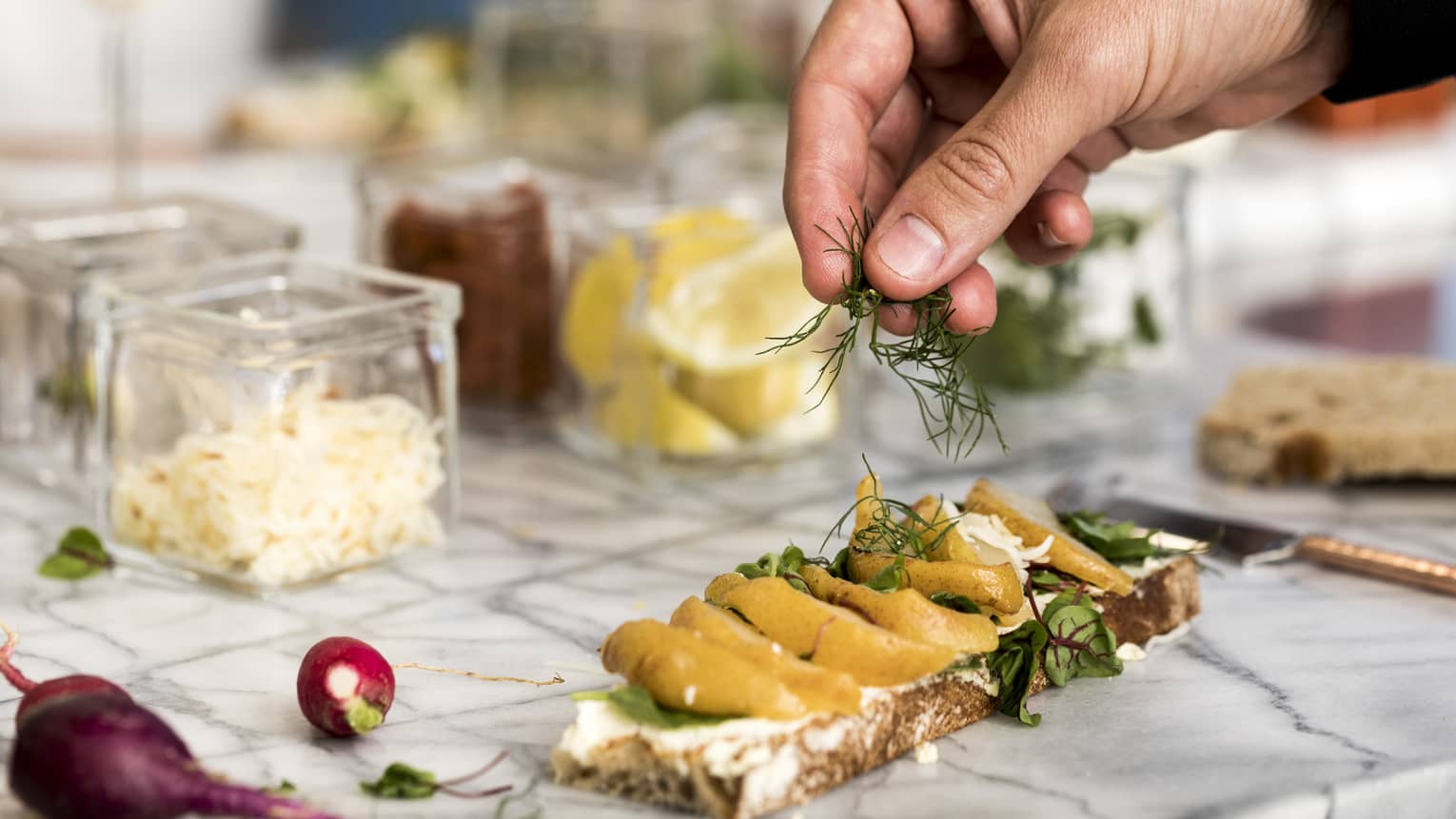 Culinary class, close-up of hand garnishing herbs on gourmet flatbread near ingredients 