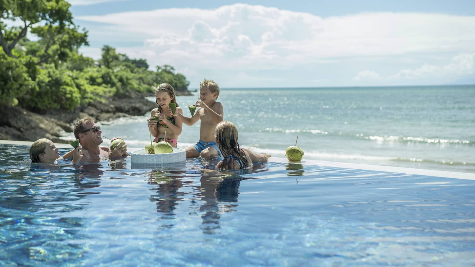 A family enjoying fresh coconuts outside in the Sundara pool