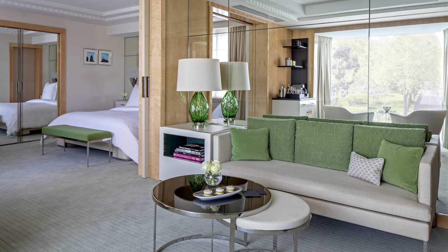 Mayfair Suite grey sofa with green pillows, round tables, alcove with bed, mirror