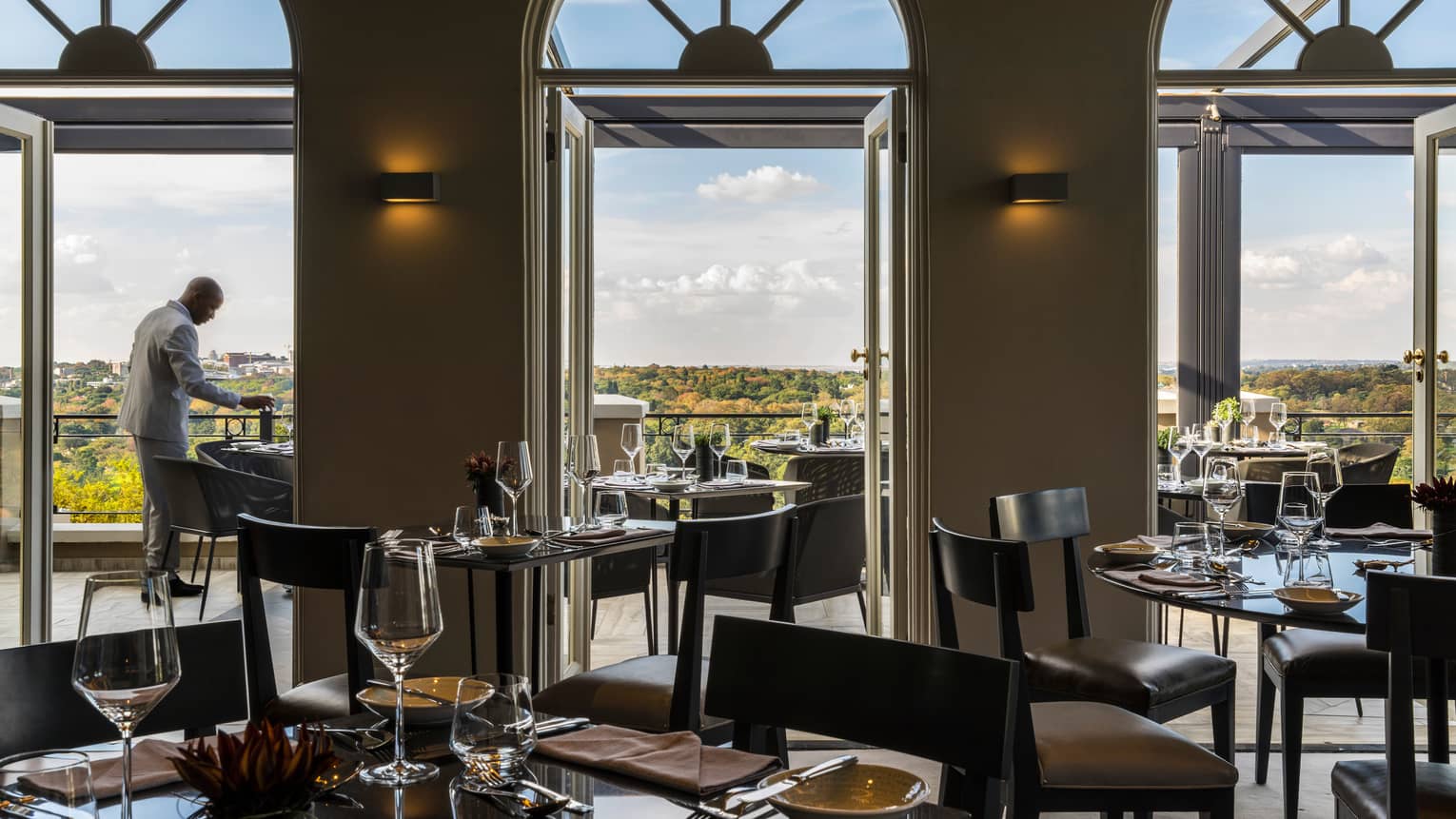 Silhouette of man in suit at patio dining table past restaurant windows and doors with archways