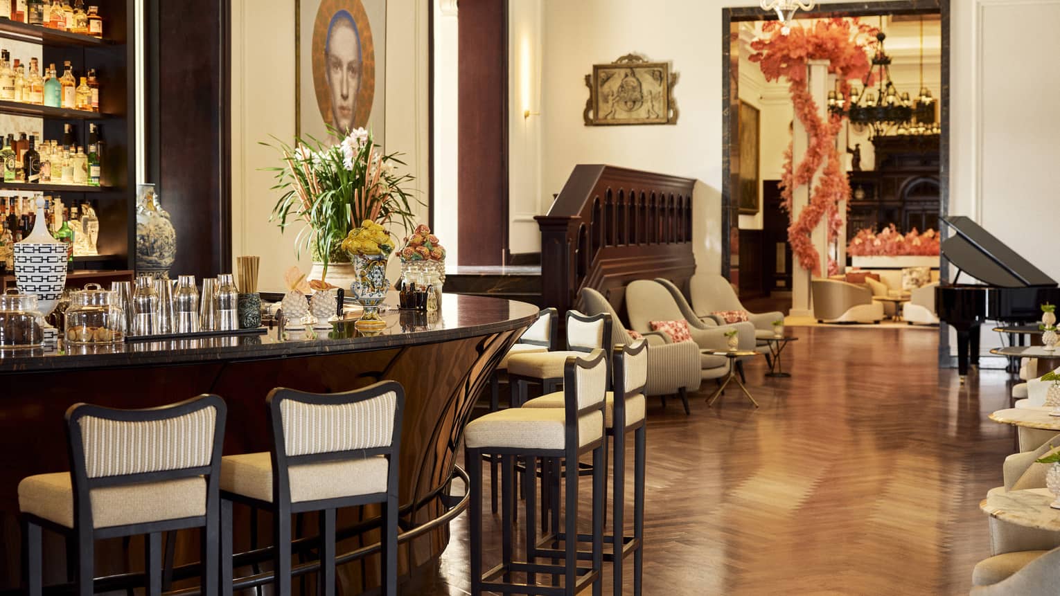 Curved bar counter with six upholstered stools pulled up to it, with other seating nearby and a black grand piano in the corner of the room
