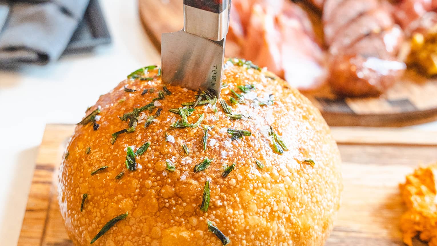 A large loaf of bread with green herbs on top.
