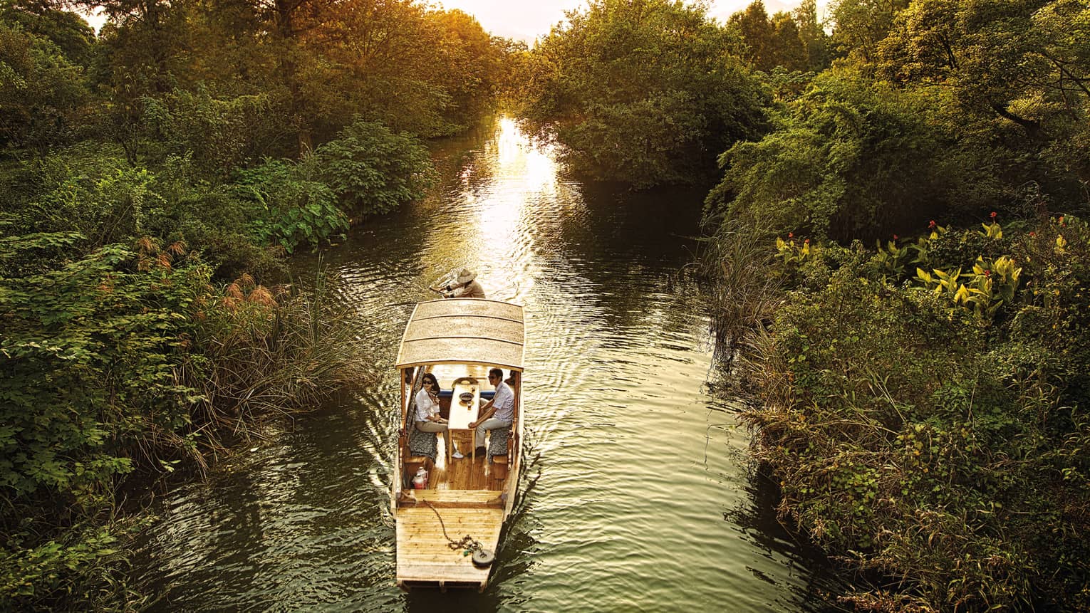 Couple in Chinese wooden row boat travelling through West Lake marsh