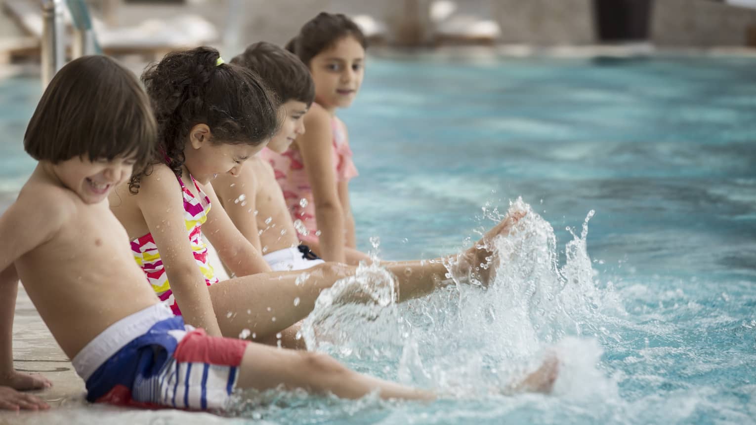 Several children splashing at the pool.