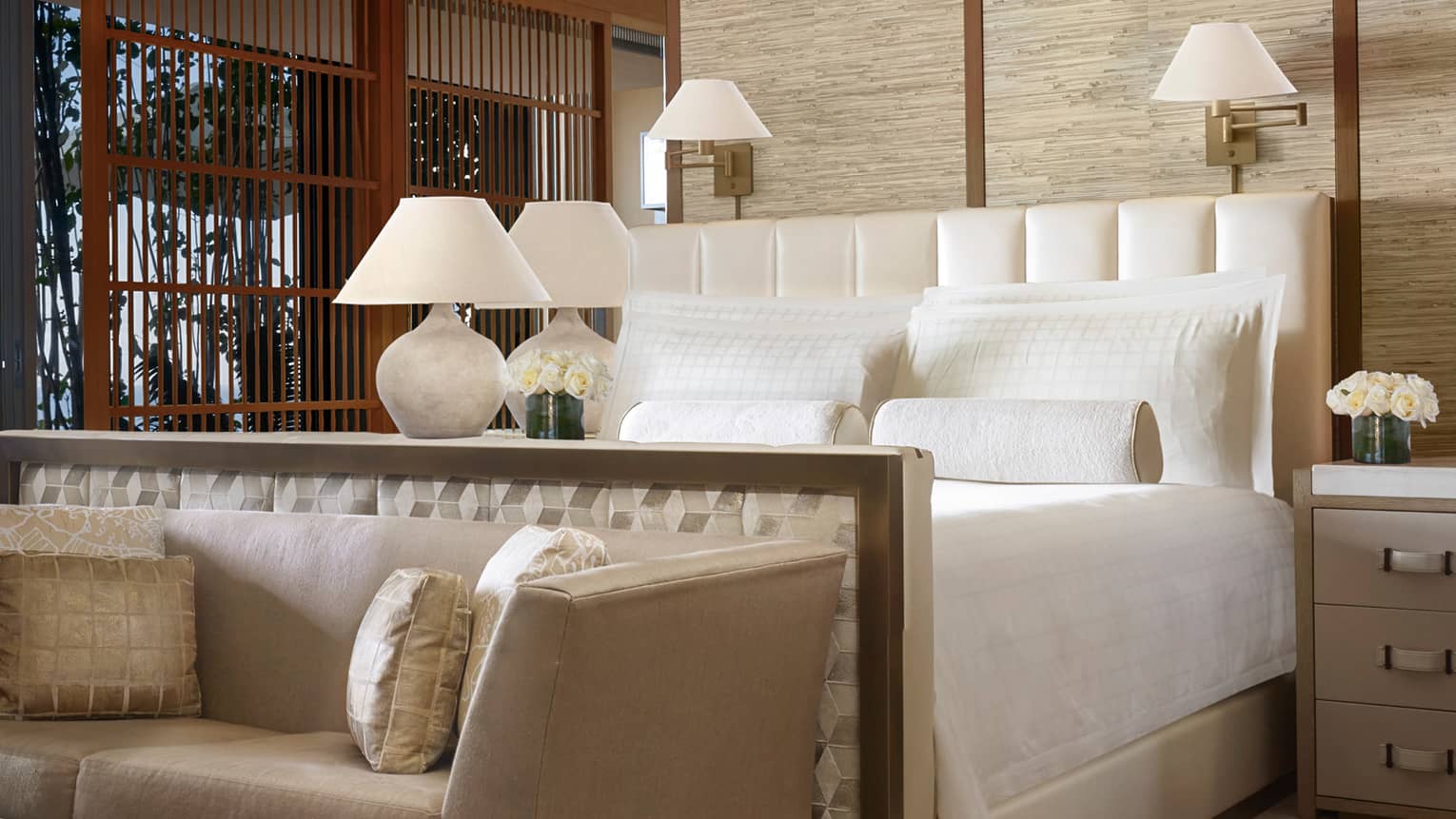 Kapihaa Presidential Suite bed, white lamp, flowers, plush chaise and pillows at foot