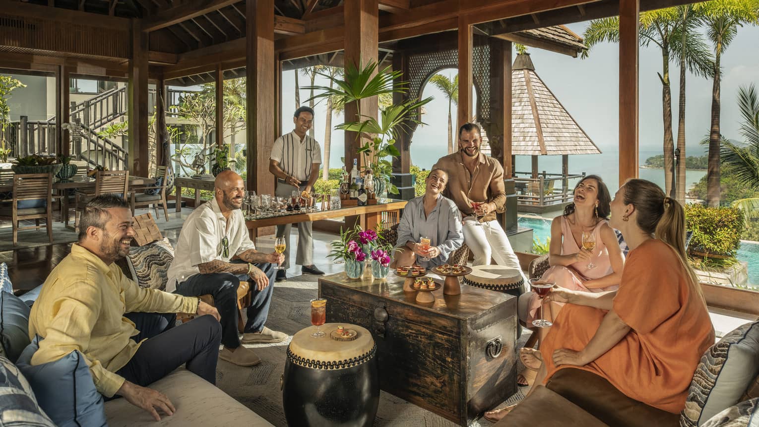 Laughing group of friends enjoy drinks made by their private bartender