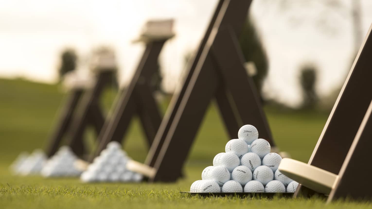 Stacks of white golf balls on lawn in front of wood panels