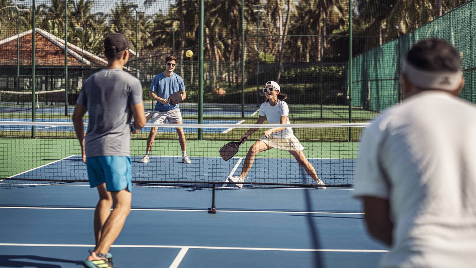 Group of 4 people play pickleball on artificial turf court