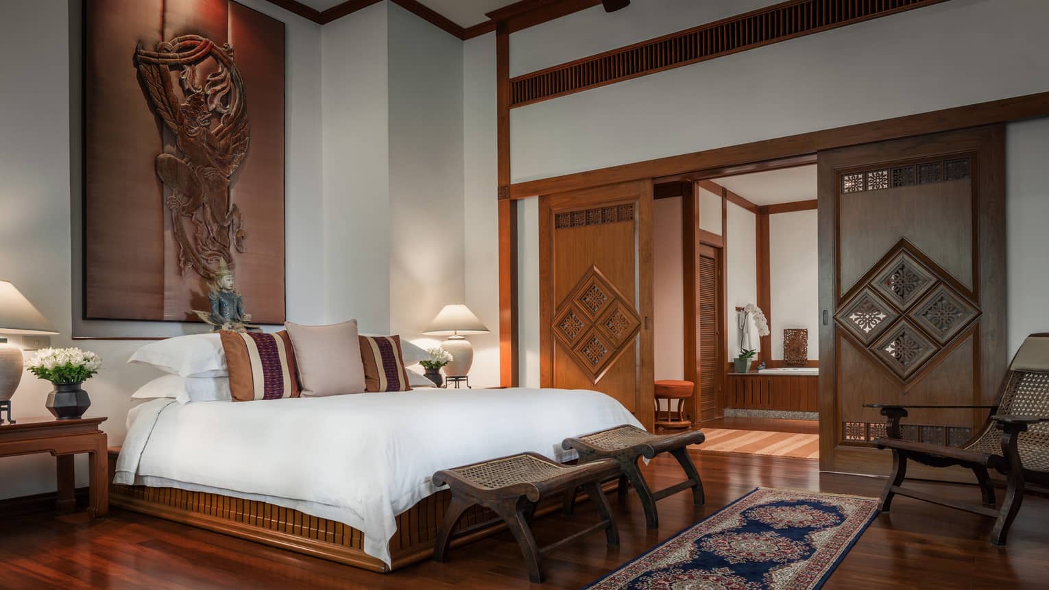 Penthouse Residence bedroom with high ceilings, wood sculpture over bed, sliding wood doors