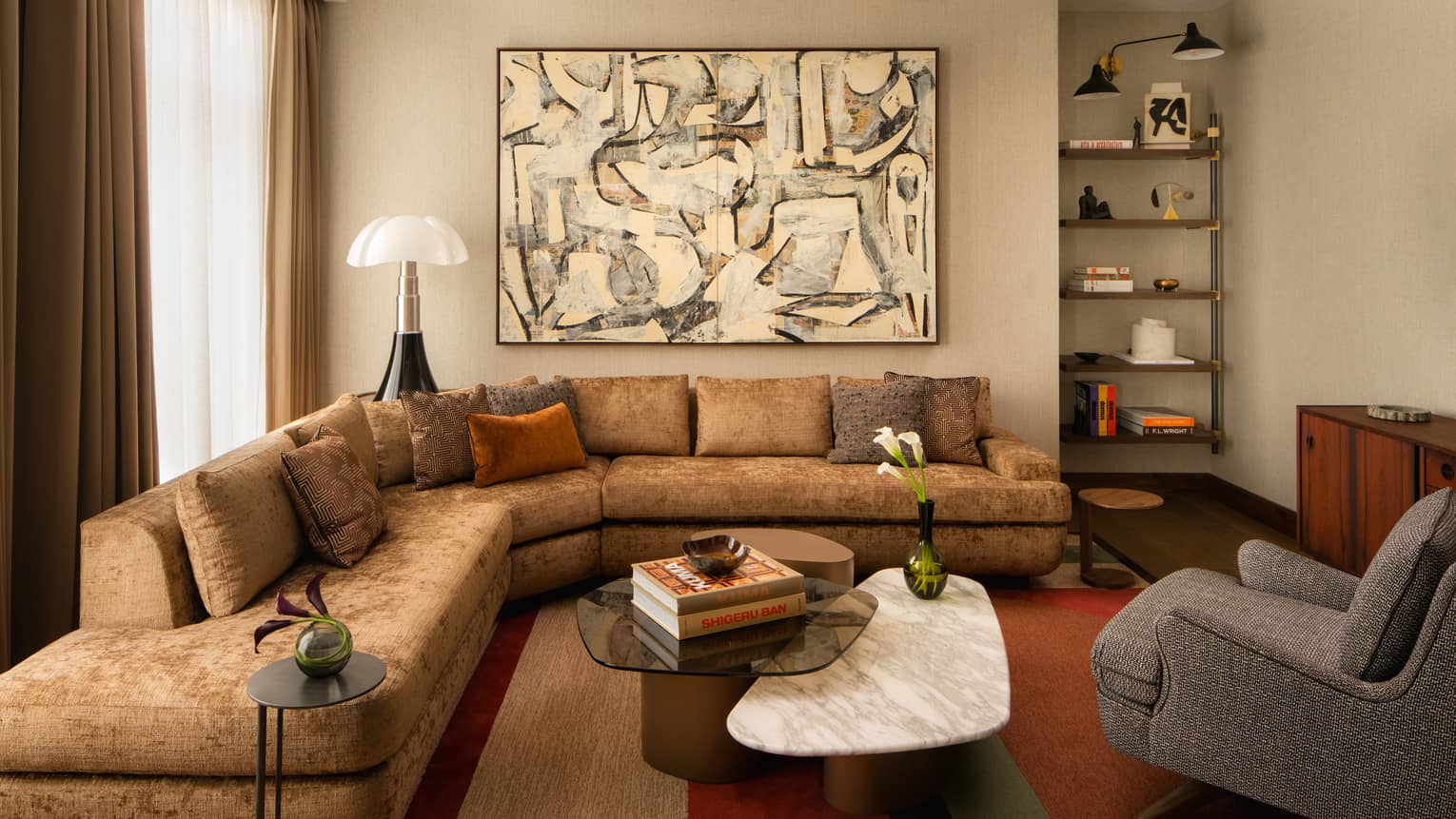 Contemporary living room of a hotel suite, with large sectional sofa, marble coffee table, abstract artwork and arm chair
