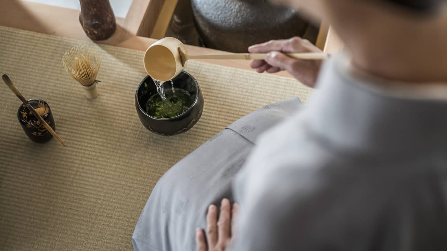 Woman kneels and pours tea from ladle during Tea Ceremony