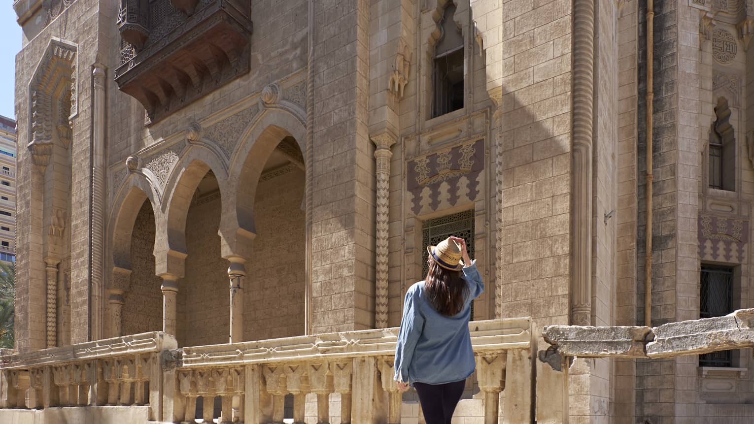 Woman looks up at historic palace exterior in Alexandria, Egypt 