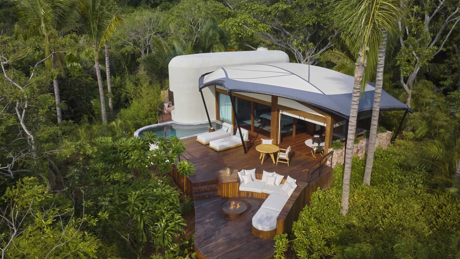 Aerial view of a luxury tent with pool and firepit in the jungle