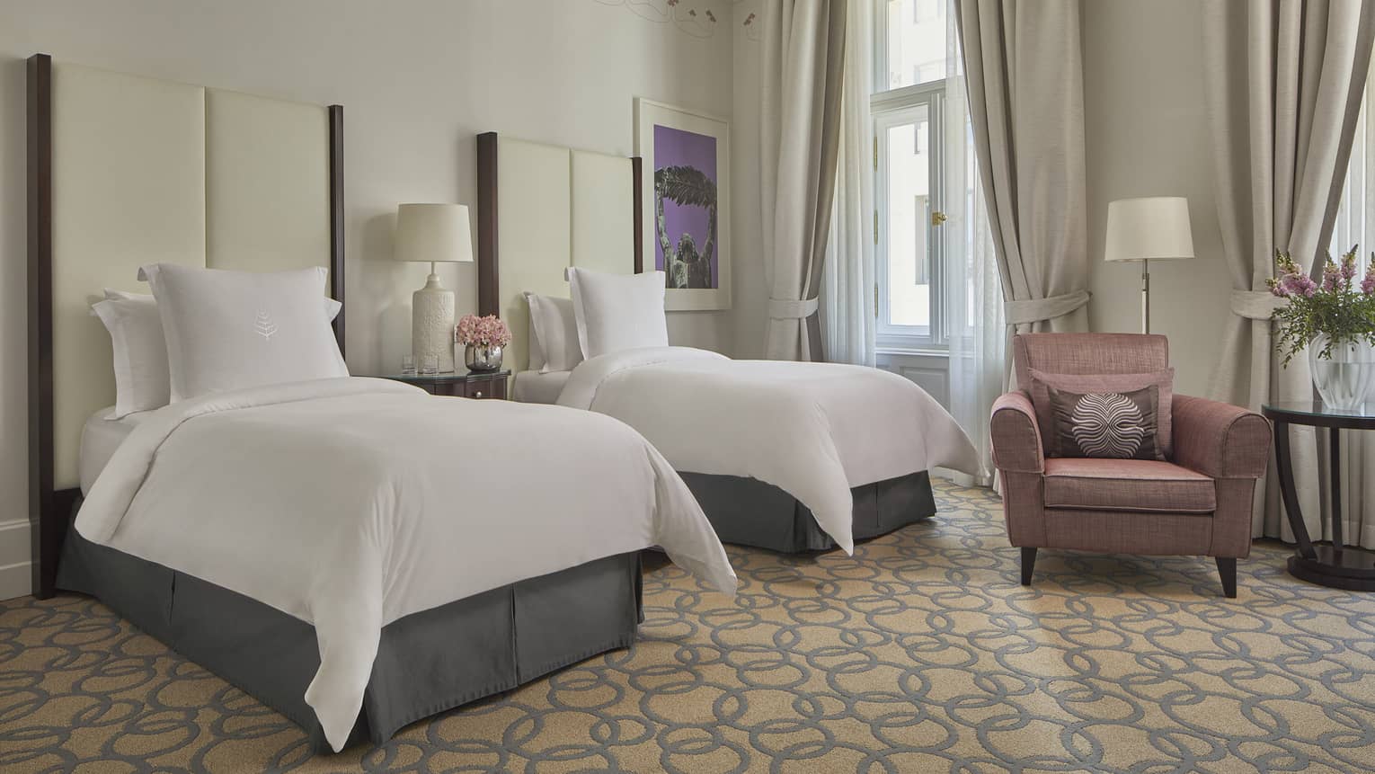Room with two white twin beds with tall headboards, mauve club chair and floor lamp