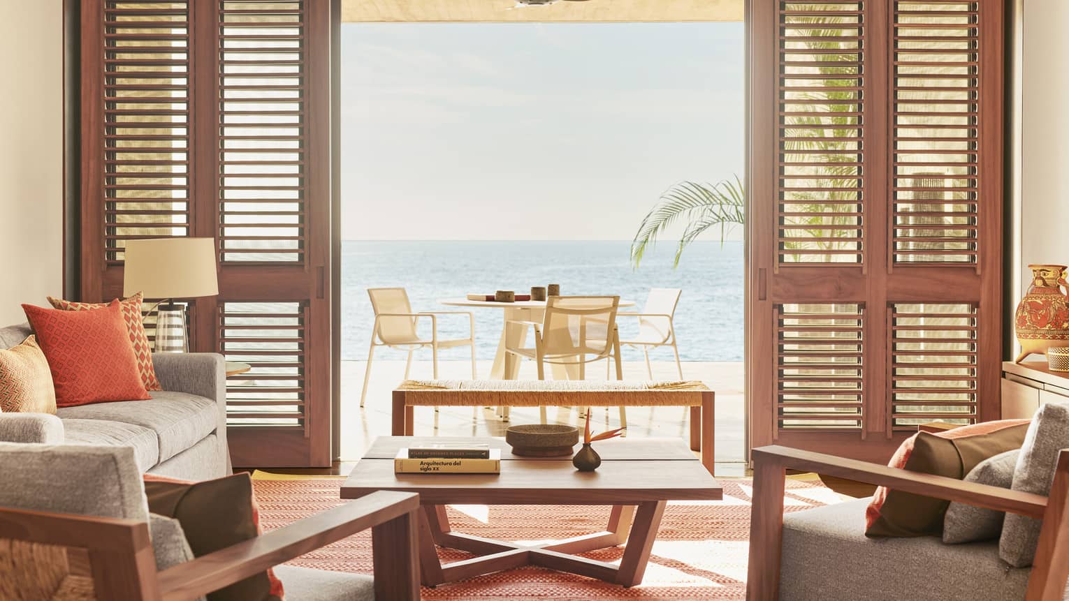 A room interior with an open door looking out at a small table with the ocean in the distance.
