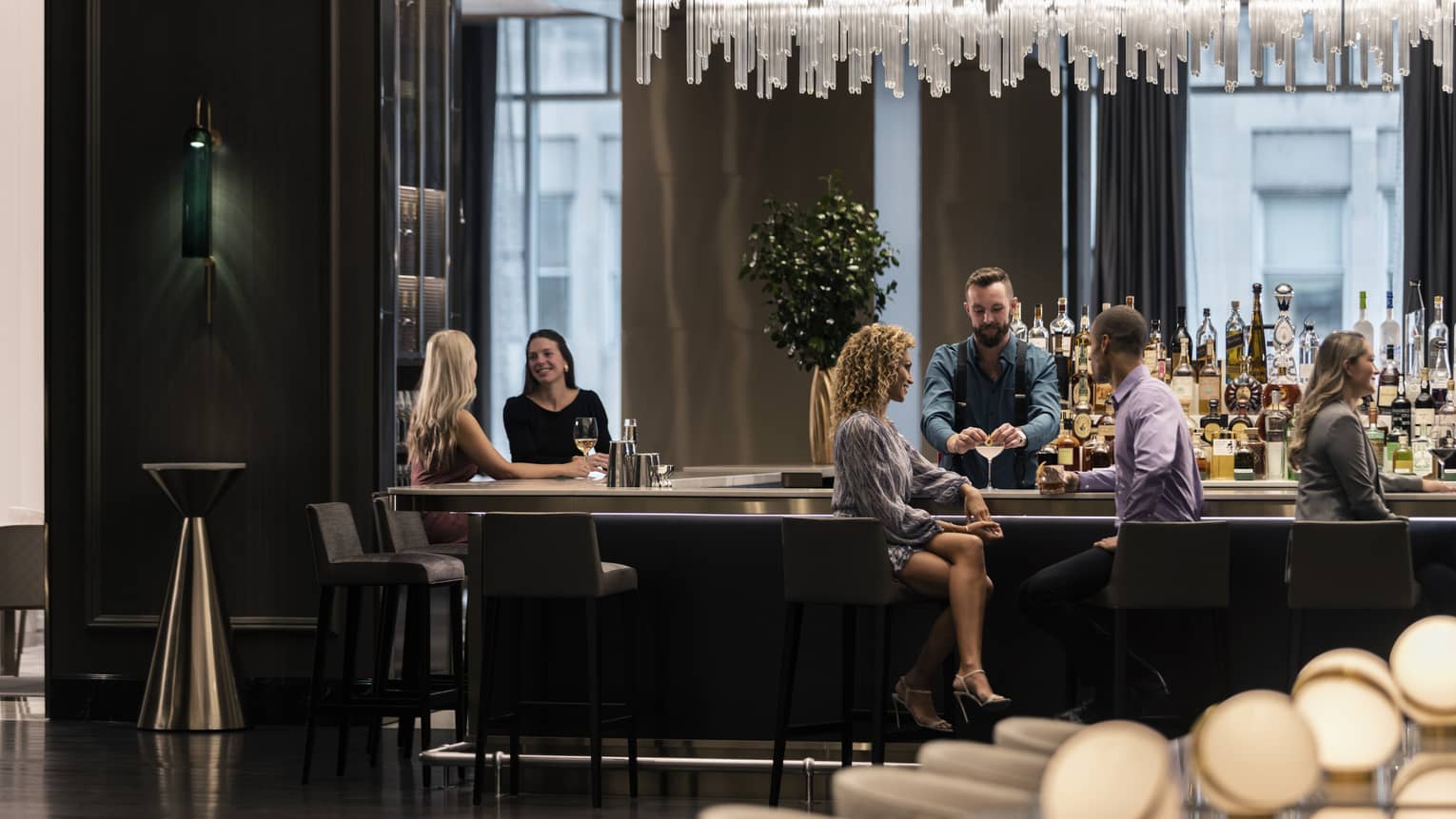 People sitting at a bar conversing and enjoying drinks.