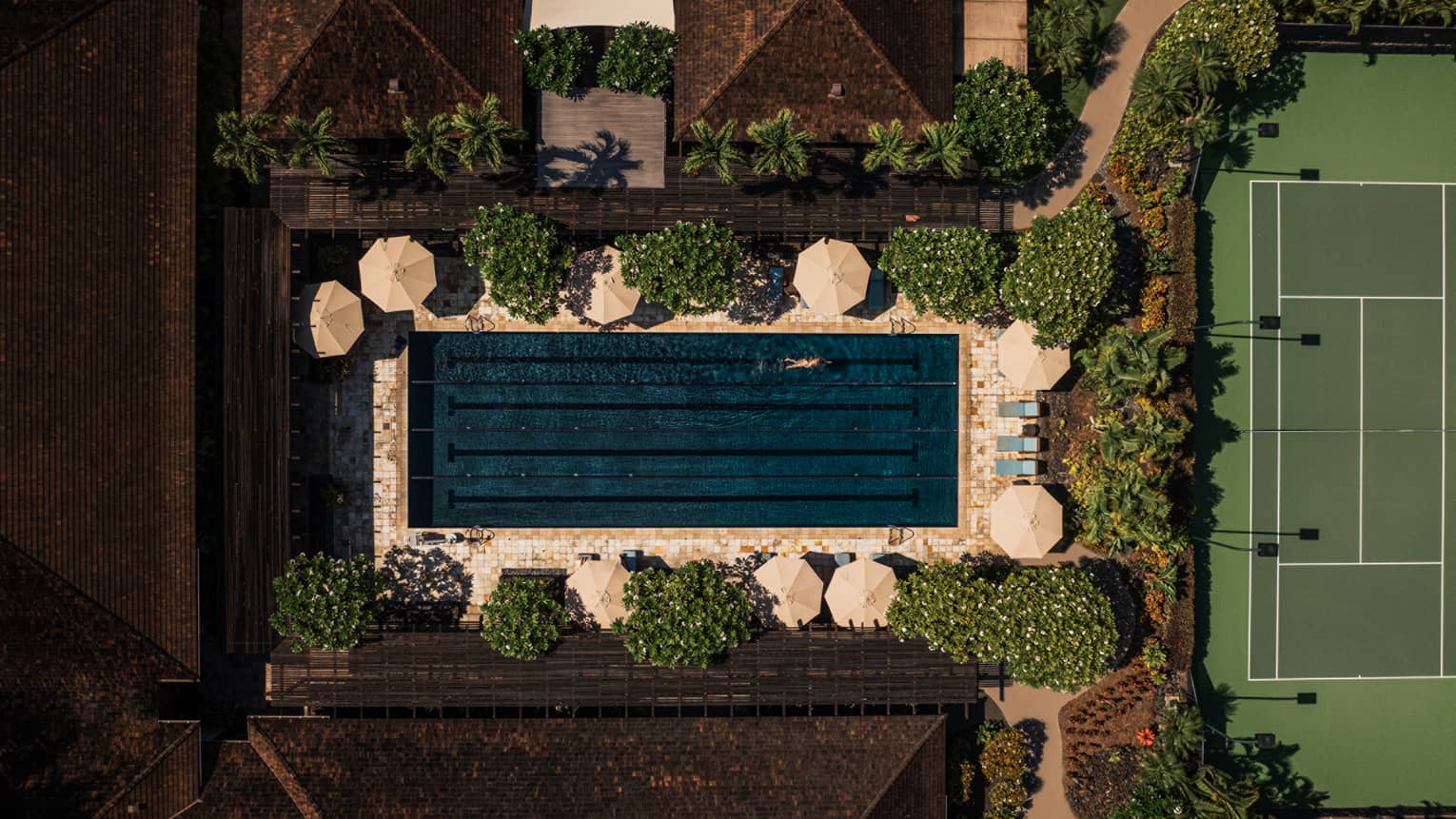 Aerial view of rectangular resort pool, near tennis court