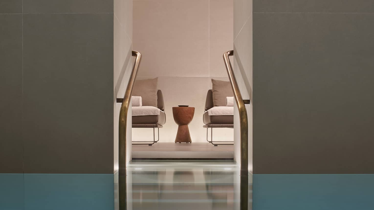 Two chairs and small table as seen from Milan Spa lap pool staircase with railings